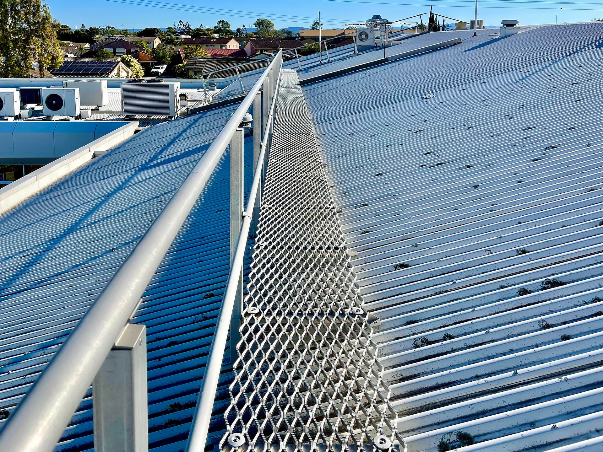 A Queensland roof walkway with guard railing, the sort of permanent edge protection that most suburban restorations never have and must therefore replace with temporary systems.